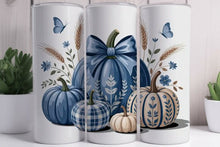 Load image into Gallery viewer, Three white cylindrical decorative vases with a coordinated autumn print featuring blue pumpkins, a plaid pumpkin, a small cream pumpkin, wheat stalks, blue flowers, and butterflies, displayed on a tabletop with potted plants in the background.
