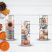 Load image into Gallery viewer, Three insulated tumbler cups with matching autumn-themed wraparound prints are displayed on a white wood plank background with decorative pumpkins, leaves, and a pine cone. The designs feature text such as 'just a GIRL who loves Fall' and include illustrations of stacked books, sunflowers, pumpkins, hearts, and a hot coffee drink.
